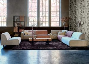Living corner Axelle designed as a spacious corner sofa with a separate element. The elements have different colors and fabrics.