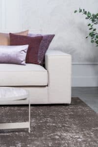 Beige hoekbank met grote hoek, gestyled met woonaccessoires in Burgundy.