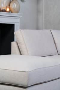 Beige hoekbank met grote hoek, gestyled met woonaccessoires in Burgundy.