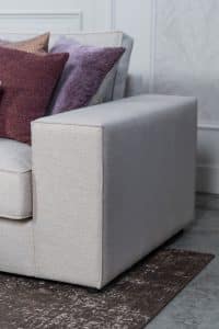 Beige hoekbank met grote hoek, gestyled met woonaccessoires in Burgundy.
