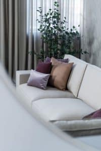 Beige hoekbank met grote hoek, gestyled met woonaccessoires in Burgundy.