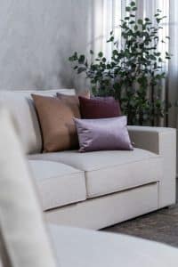 Beige hoekbank met grote hoek, gestyled met woonaccessoires in Burgundy.