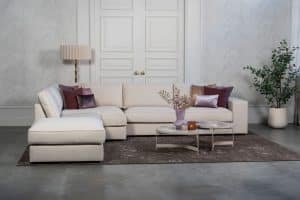 Beige hoekbank met grote hoek, gestyled met woonaccessoires in Burgundy.
