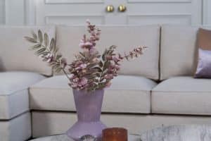 Beige hoekbank met grote hoek, gestyled met woonaccessoires in Burgundy.