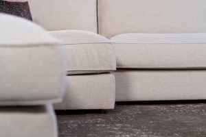 Beige hoekbank met grote hoek, gestyled met woonaccessoires in Burgundy.