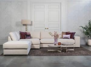 Beige hoekbank met grote hoek, gestyled met woonaccessoires in Burgundy.