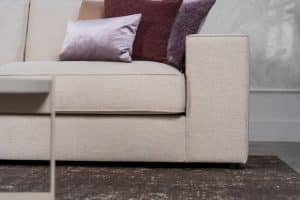 Beige hoekbank met grote hoek, gestyled met woonaccessoires in Burgundy.