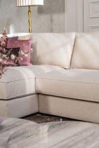 Beige hoekbank met grote hoek, gestyled met woonaccessoires in Burgundy.