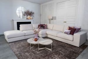 Beige hoekbank met grote hoek, gestyled met woonaccessoires in Burgundy.
