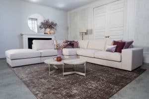 Beige hoekbank met grote hoek, gestyled met woonaccessoires in Burgundy.