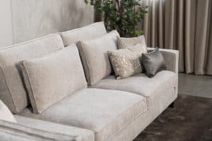 Hoekbank Gigi in een neutrale beige kleur, gestyled met accessoires in warme aardetinten.