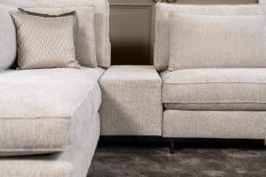 Hoekbank Gigi in een neutrale beige kleur, gestyled met accessoires in warme aardetinten.