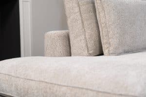 Hoekbank Gigi in een neutrale beige kleur, gestyled met accessoires in warme aardetinten.