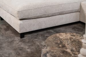 Hoekbank Gigi in een neutrale beige kleur, gestyled met accessoires in warme aardetinten.