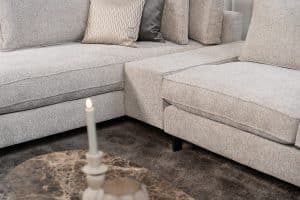 Hoekbank Gigi in een neutrale beige kleur, gestyled met accessoires in warme aardetinten.